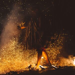 smooky image of a person in a dark robe walking through fire. by joshua newton